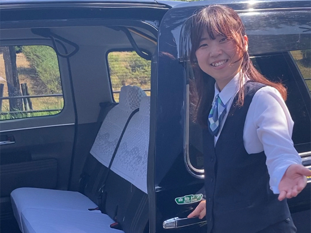 お客様の乗車を手伝うタクシードライバーの女性写真