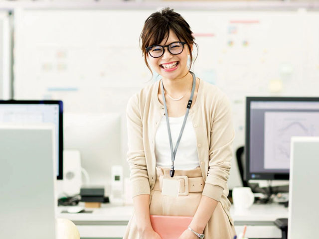 黒縁メガネの笑顔の女性／オフィス内