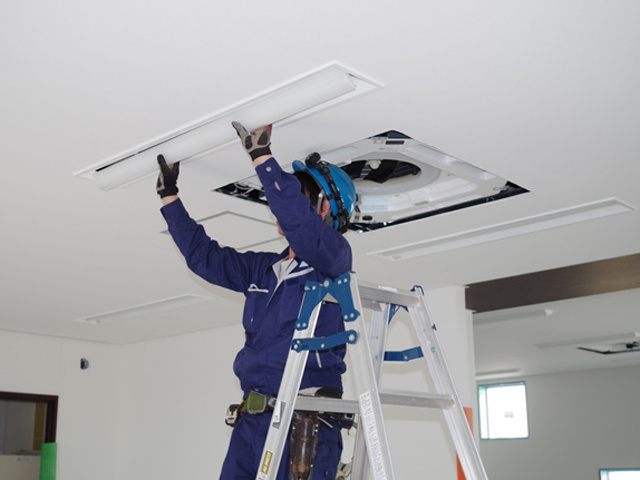 オフィスで照明の工事をする男性作業員