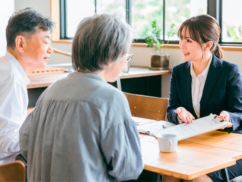 シニア世代の夫婦に商品を説明する営業の女性