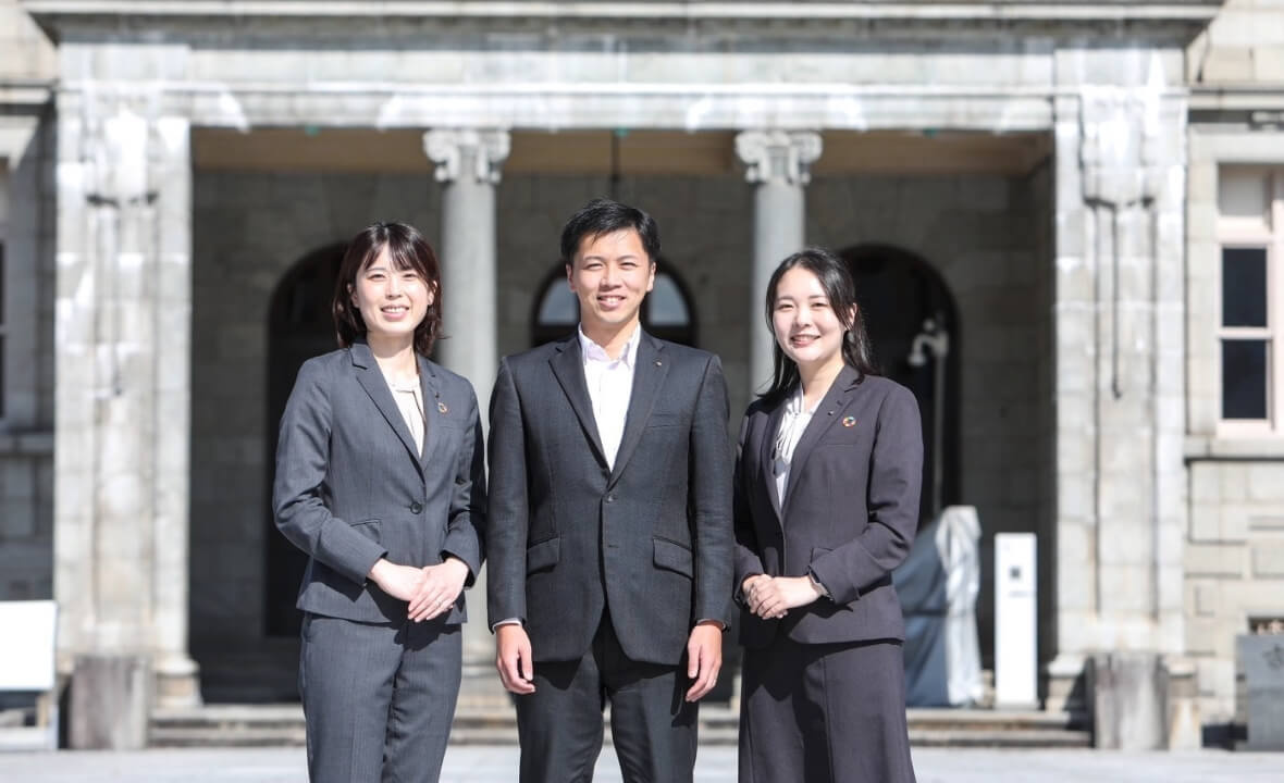 笑みを浮かべるスーツ姿の男女3人の写真