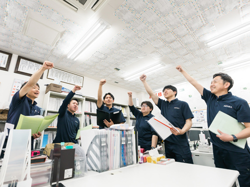 こぶしを上げて結束している社員たち