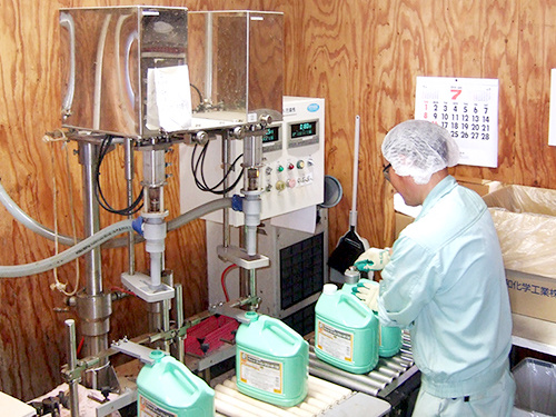 製造された薬品ボトルのフタを閉めている作業スタッフの写真。直治薬品株式会社