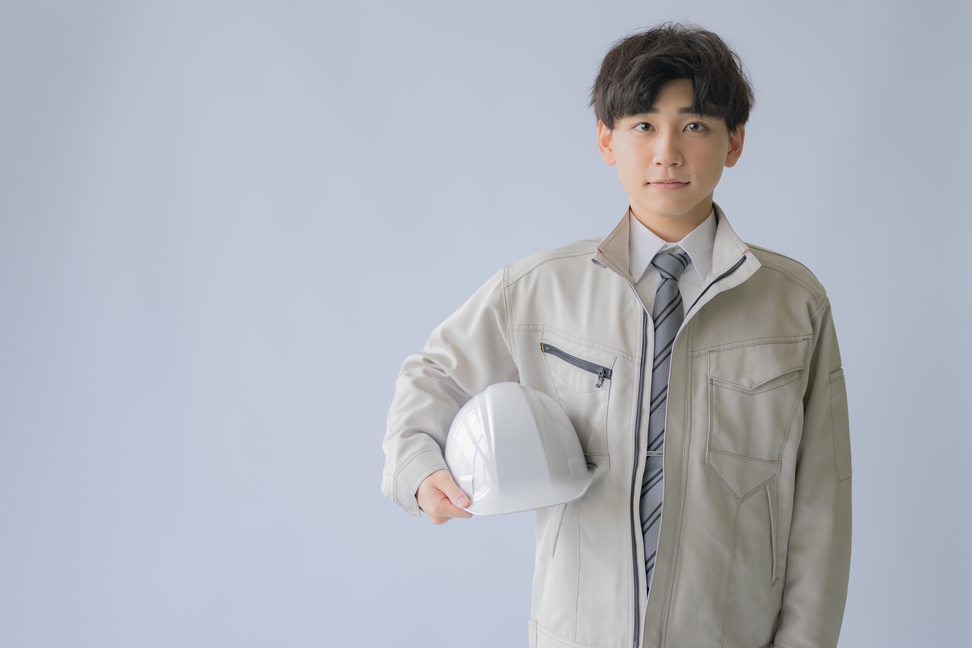 作業服でヘルメットを抱えた男性スタッフの写真