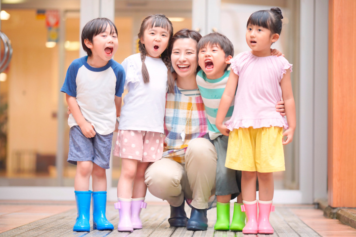 4人の園児を笑顔で抱き寄せる女性の写真