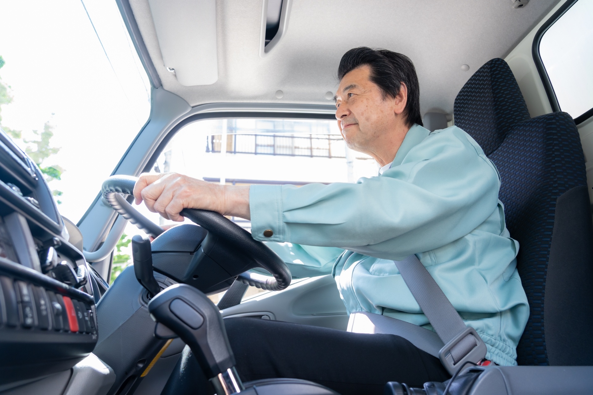 車を運転している作業服姿の中高年男性写真
