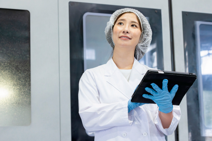 タブレットを持ち上を見上げる女性スタッフの写真