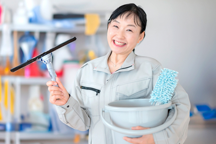 掃除道具と笑顔の中高年女性スタッフ