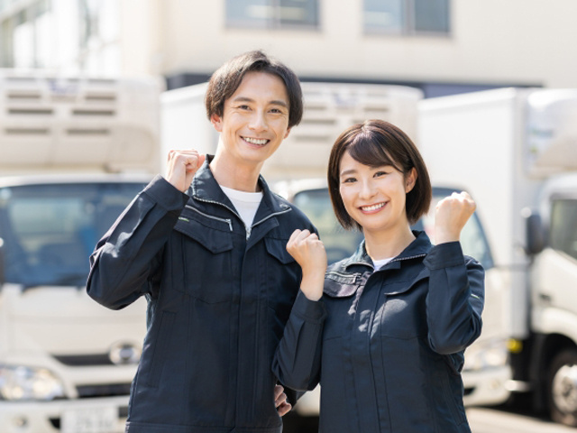 トラックの前に立ち笑顔でガッツポーズをする男女スタッフ