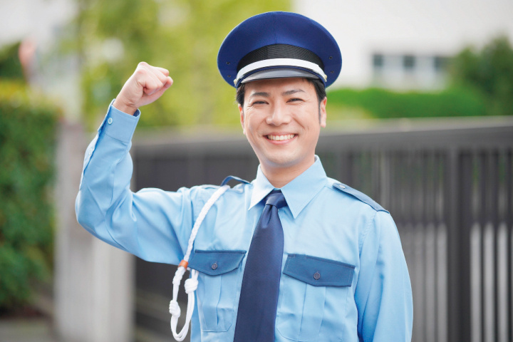 笑顔でガッツポーズをする男性警備員の写真