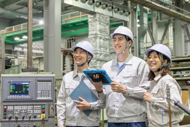 作業服を着てパソコンを操作する男女の写真