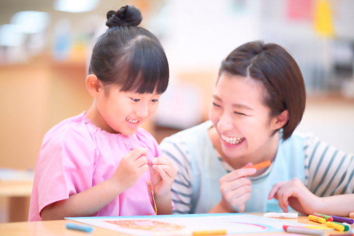 子供とお絵描きをする保育士