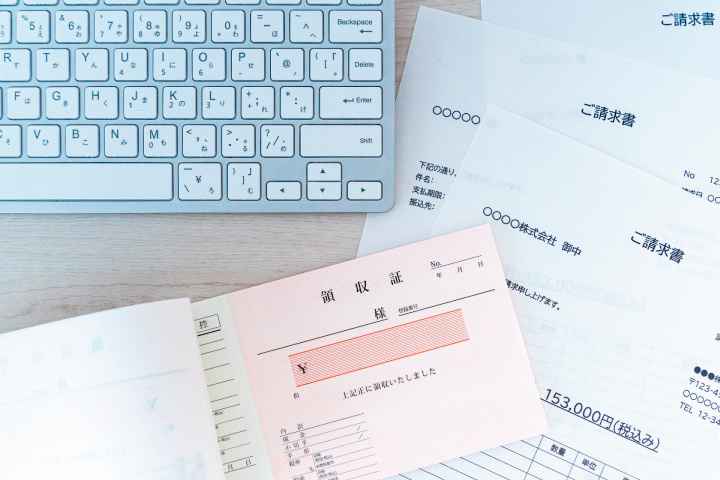 領収書や請求書などの経理書類とパソコンの写真