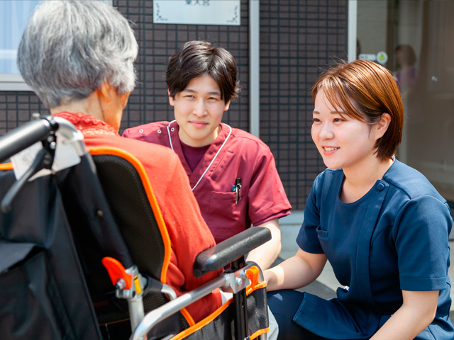 女性入居者と会話をする男女の看護師