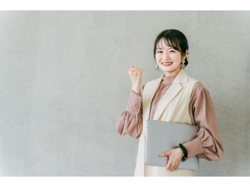 オフィスカジュアルでパソコンを持っている女性